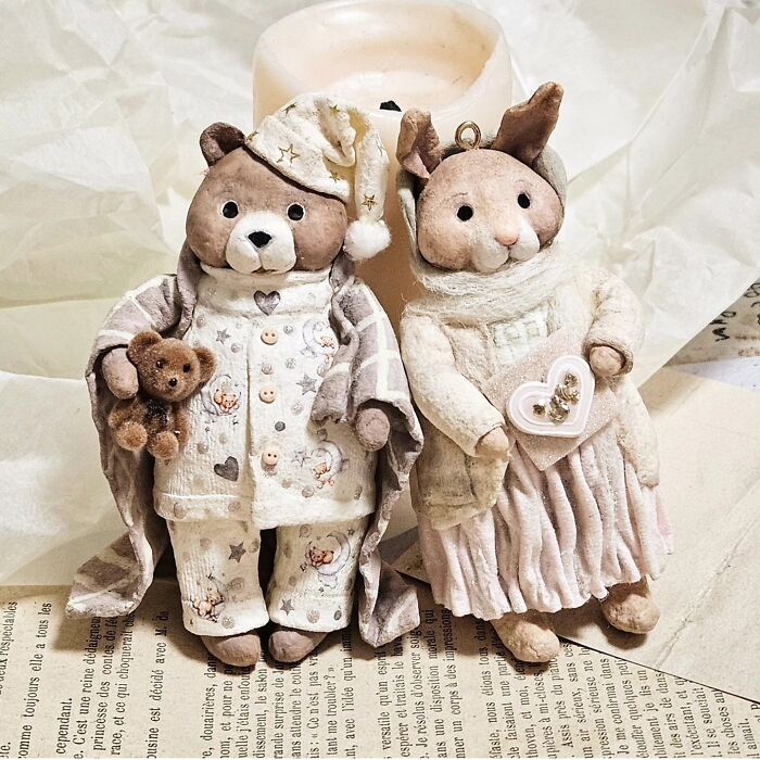 Two handmade cotton wool creations: a bear in pajamas with a teddy, and a bunny in a dress holding a heart.
