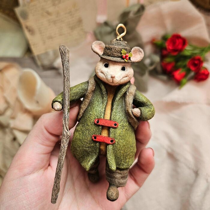 A handmade cotton wool creation of a mouse in a green coat and hat, holding a walking stick.