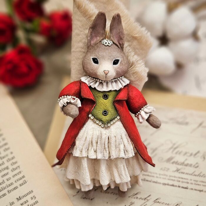 A handmade cotton wool creation of a rabbit in a red and green historical-style outfit.