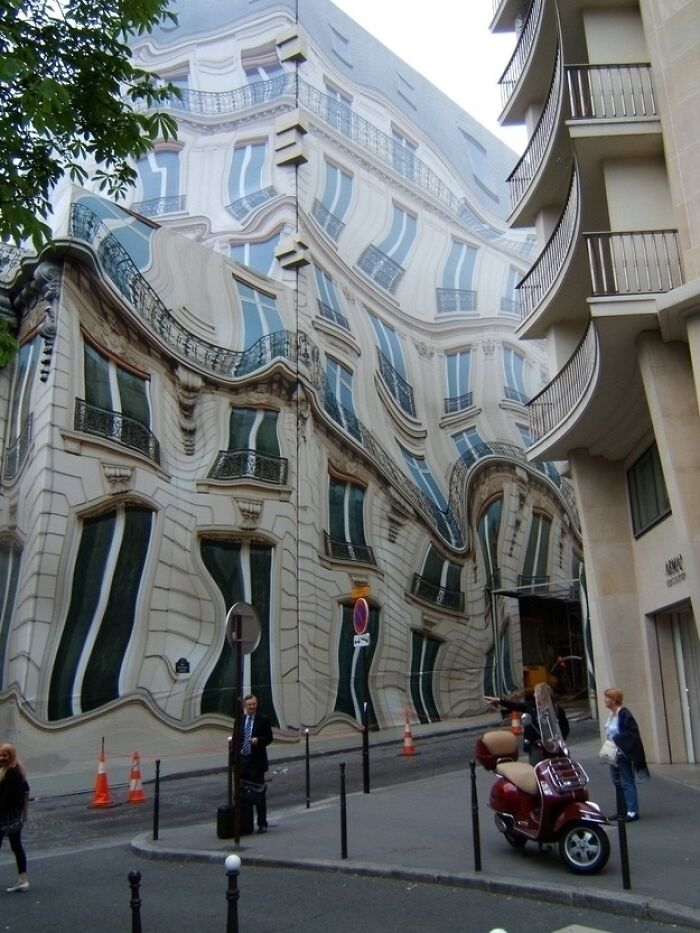 A building with an optical illusion painting that makes it appear warped, a real photo that makes your brain question if it was edited.