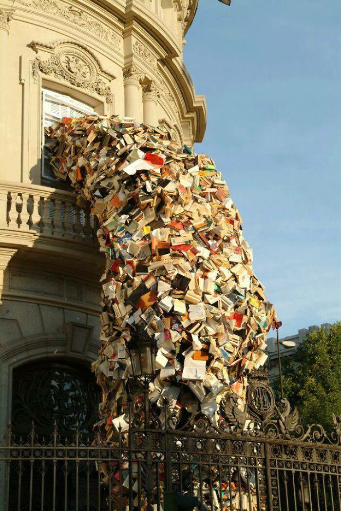 Hundreds of books spilling out of a window and down a building, making your brain question if it was edited.