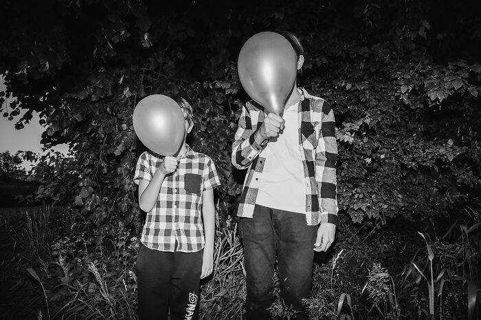 Two figures with balloons covering their faces, capturing best black and white photographs.