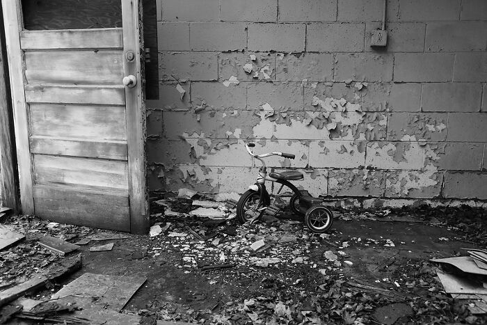 Best black and white photographs: a tricycle by a decaying wall and open door.