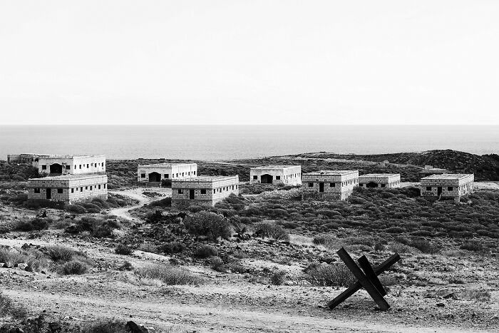 Best black and white photographs of abandoned seaside buildings and a metal barrier.