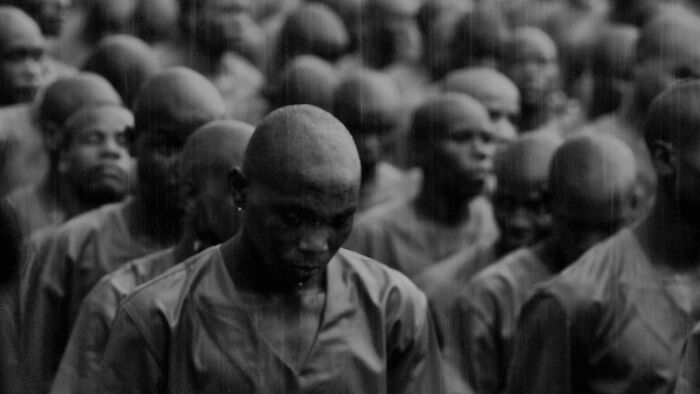 A crowd of people with shaved heads in a somber black and white photograph.