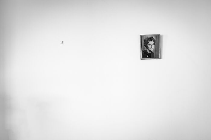A framed portrait of a smiling woman on a white wall, among the best black and white photographs.