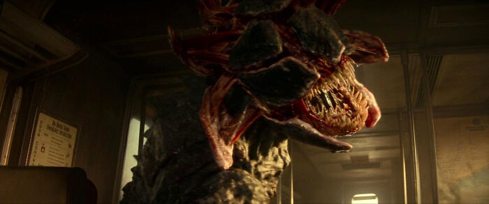 A monstrous creature with a gaping, fanged mouth inside a train, a most terrifying horror movie scene.