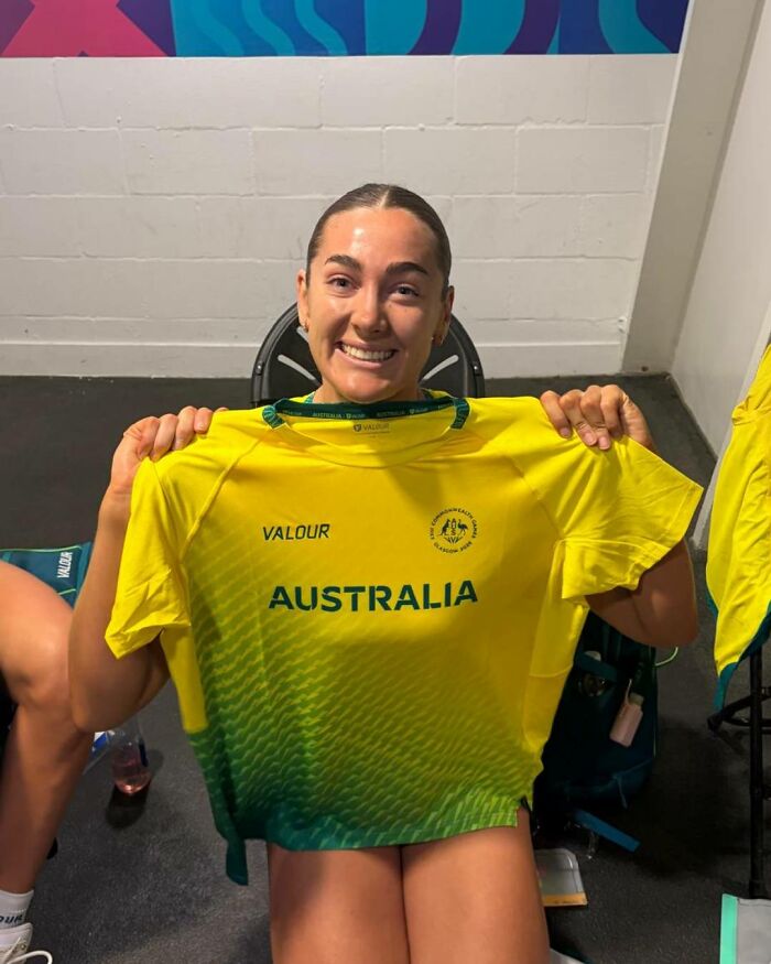 Female athlete holding up her uniform shirt, smiling despite the wardrobe malfunction.