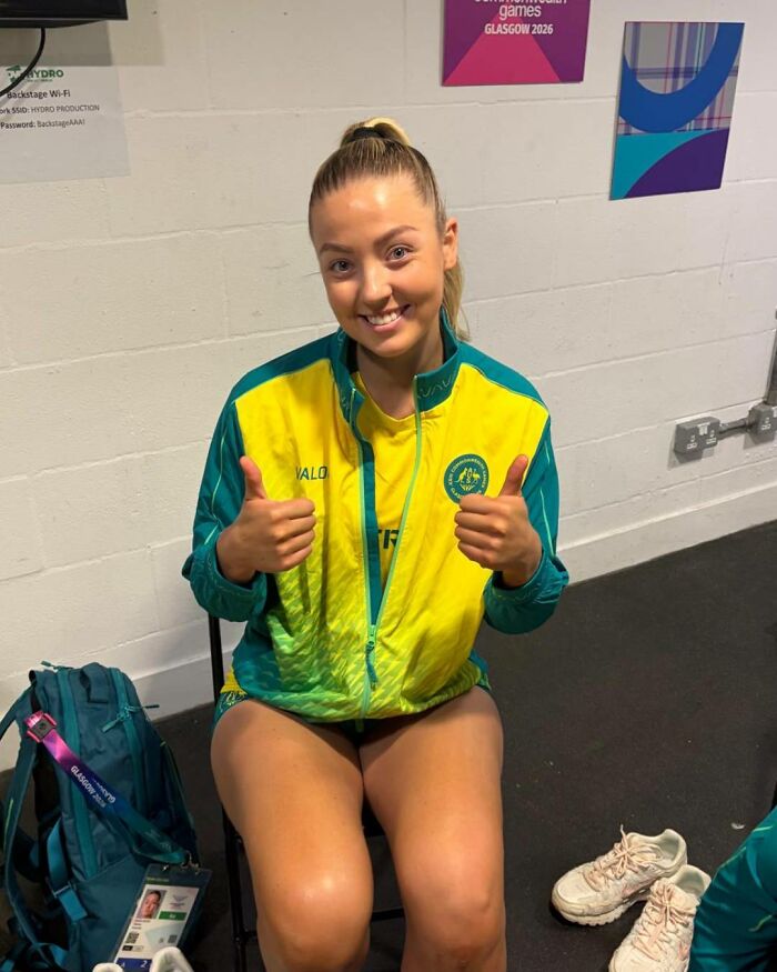 Female athlete giving thumbs up, smiling for the camera, amidst a wardrobe malfunction controversy.