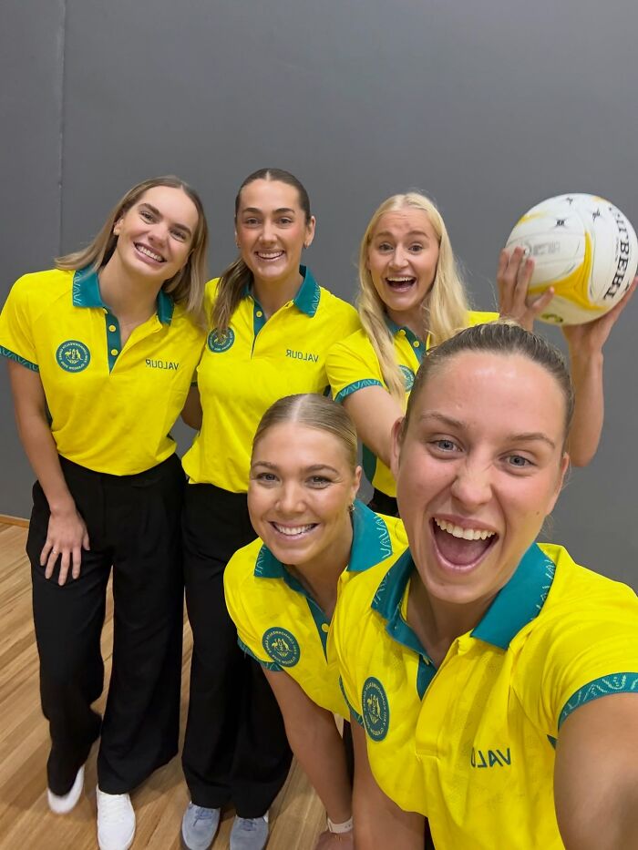 Group of smiling female athletes, some holding a netball, addressing the wardrobe malfunction incident.
