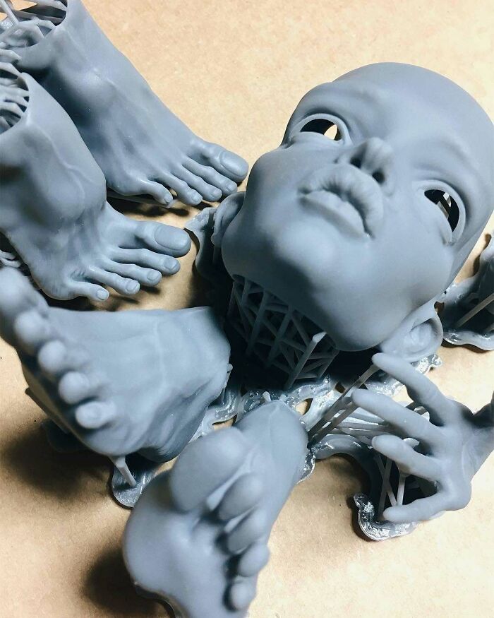 Unassembled grey 3D printing parts of a doll, including a head, hands, and feet, showing amazing creations.