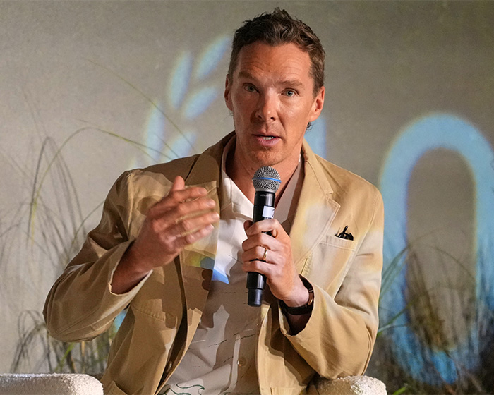 Benedict Cumberbatch, a celebrity, speaks into a microphone, discussing unsolved celebrity mysteries.