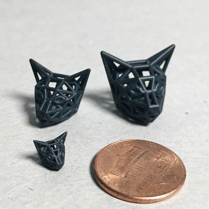 Three small, geometric 3D printing creations of cat heads next to a penny for scale. Amazing 3D printing creations.