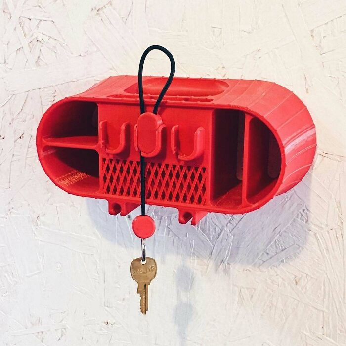 A red 3D printing creation of a wall-mounted organizer with keys hanging from it. Amazing 3D printing creations.