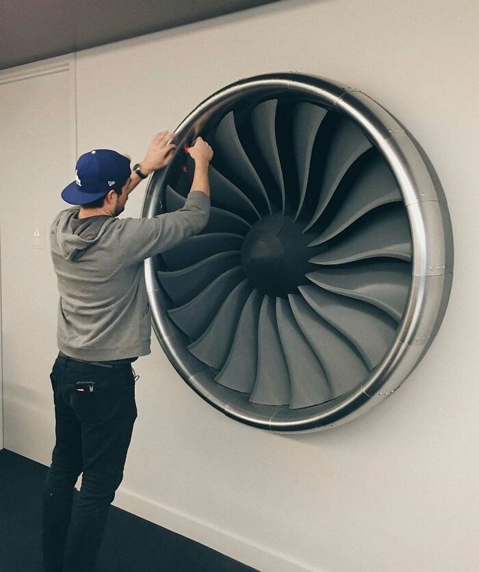 Man working on a large 3D printing jet engine replica, showcasing amazing 3D printing creations.