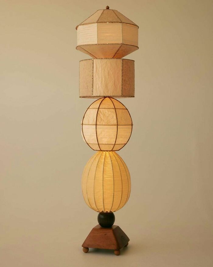 A brilliant design choice: a tall, stacked floor lamp with unique paper shades in various geometric shapes.