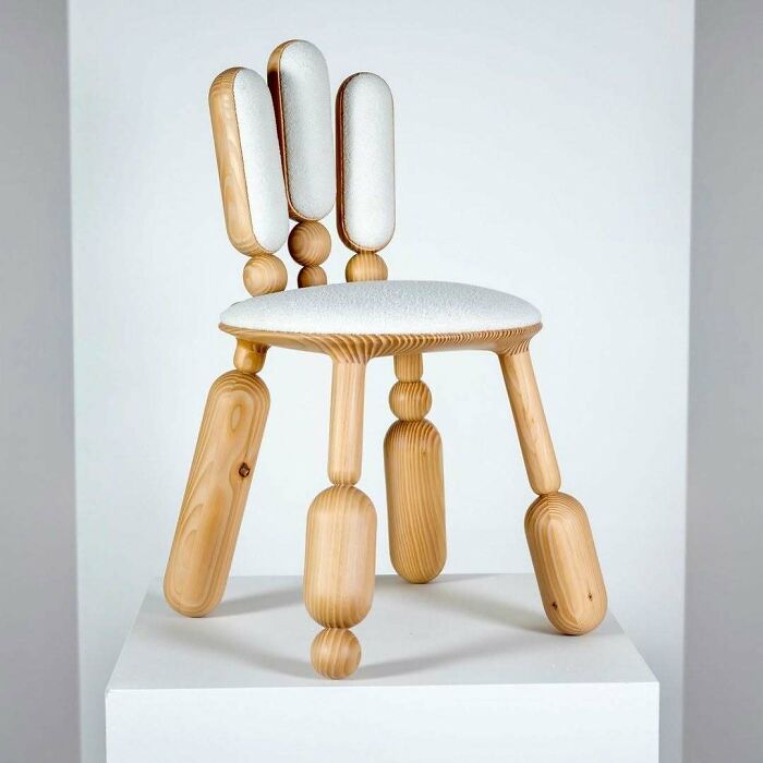 A light wooden chair with rounded legs and upholstered backrests, exhibiting brilliant design choices in innovative furniture.