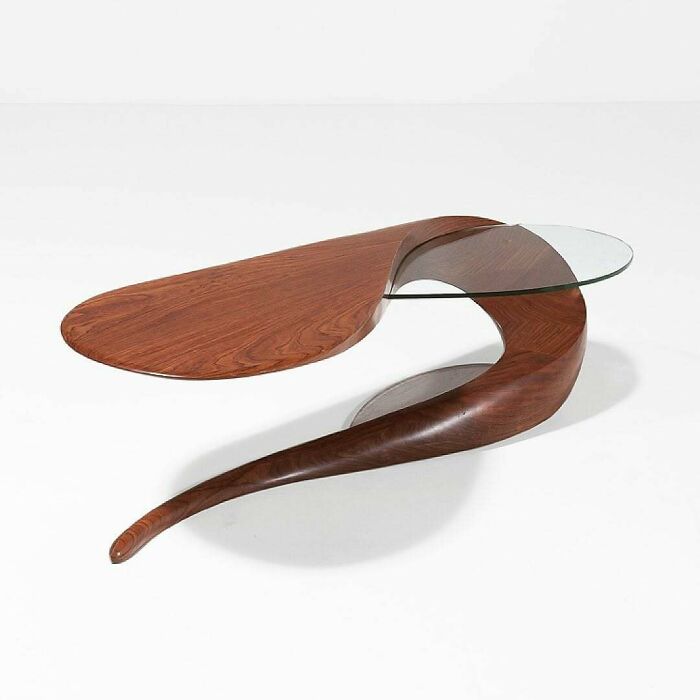 A brilliant design of a modern wooden coffee table with a flowing, sculptural base and a circular glass top, showcasing unique aesthetics.