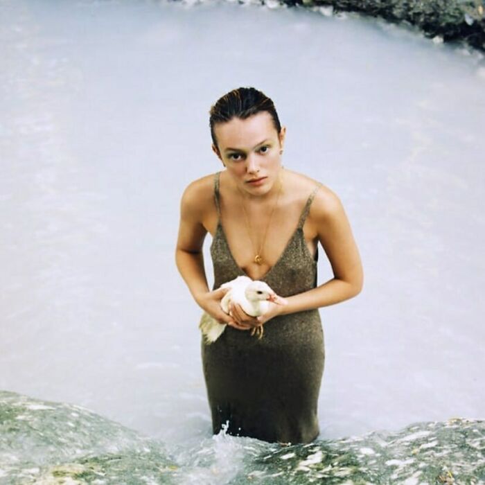 A woman in a slip dress holding a white bird in light blue water, part of bizarre content on Zara website.