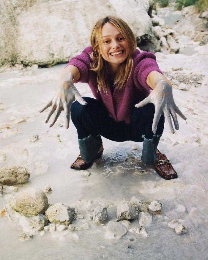 Woman with muddy hands smiling, bizarre Zara content.
