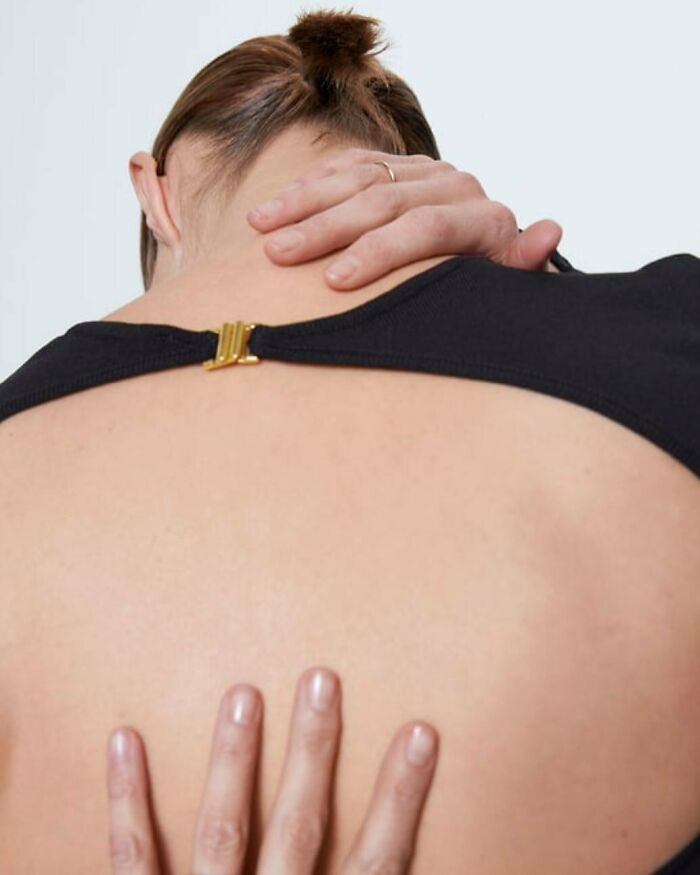 A bizarre content image from Zara website showing a person's back with hands touching it, and a golden clasp.