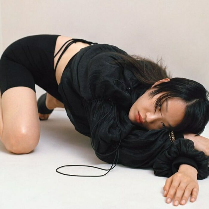 A model on hands and knees, wearing black, showcasing the bizarre content on Zara website.