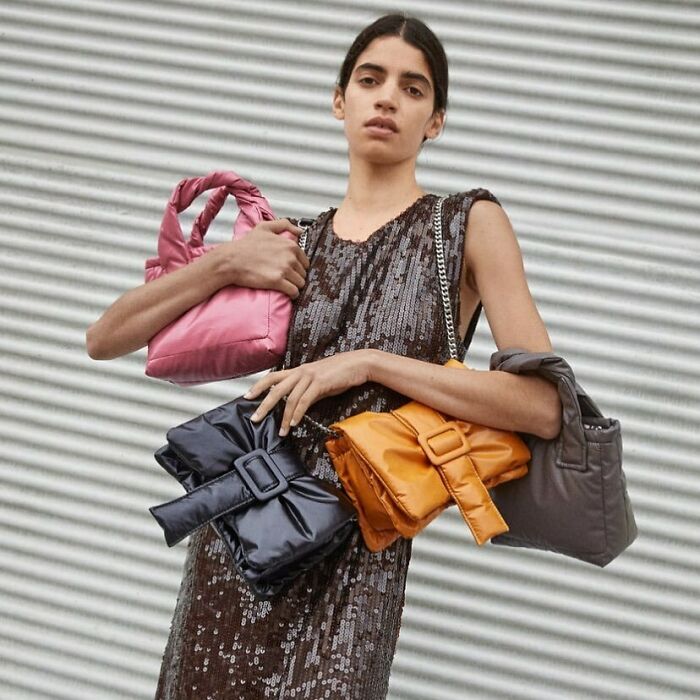 A model holding multiple handbags, showcasing the bizarre content on Zara website.