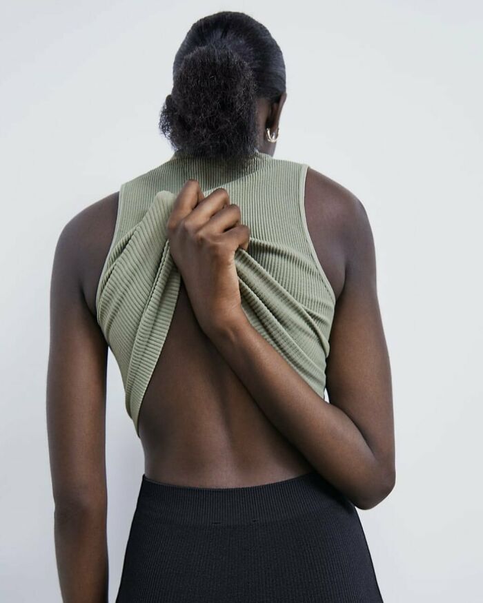 A woman from behind, adjusting a green top, part of the bizarre content on Zara website.