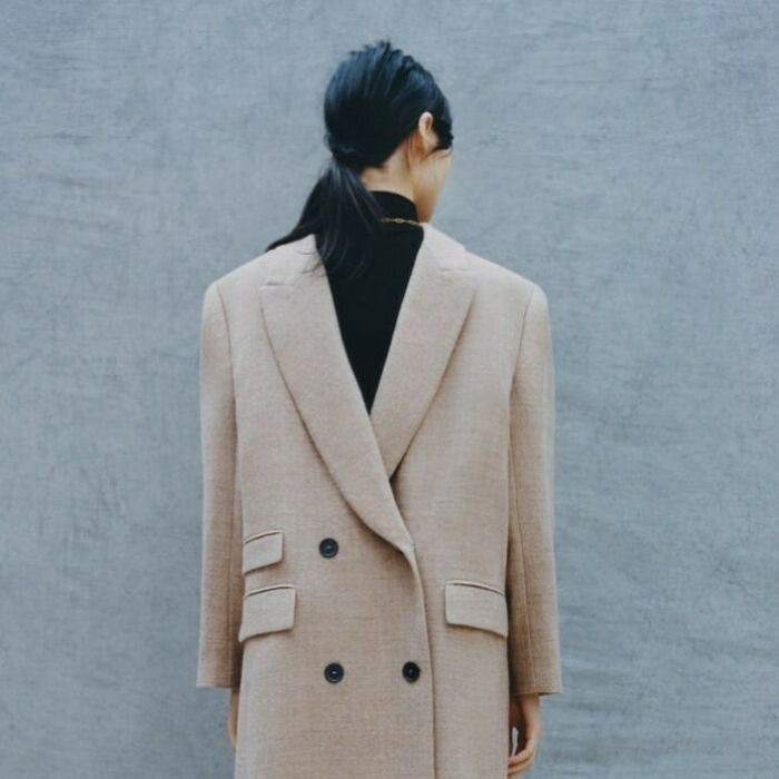 A woman wearing an oversized Zara coat, showcasing bizarre content from the Zara website.