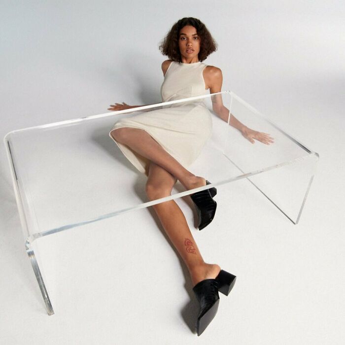 A woman poses behind a clear table for Zara content, creating a bizarre image.