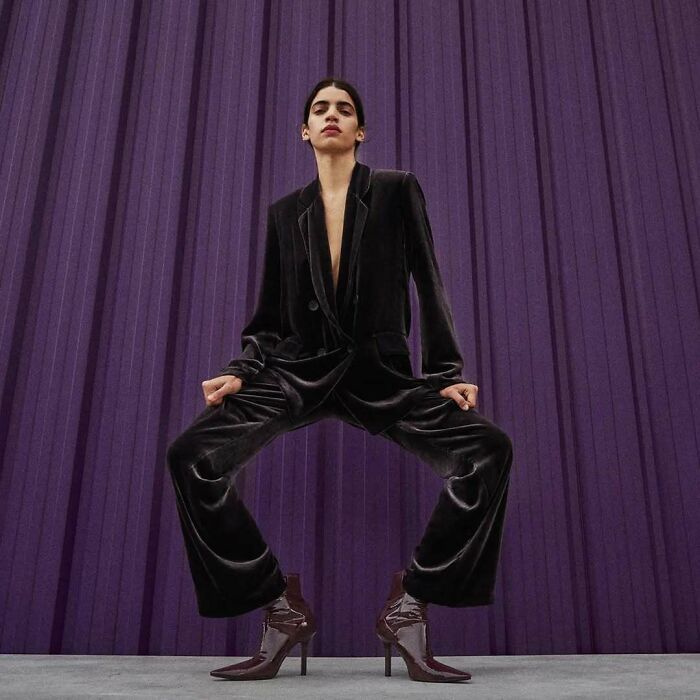 A model in a velvet suit with wide stance, against a purple background, for Zara website's bizarre content.