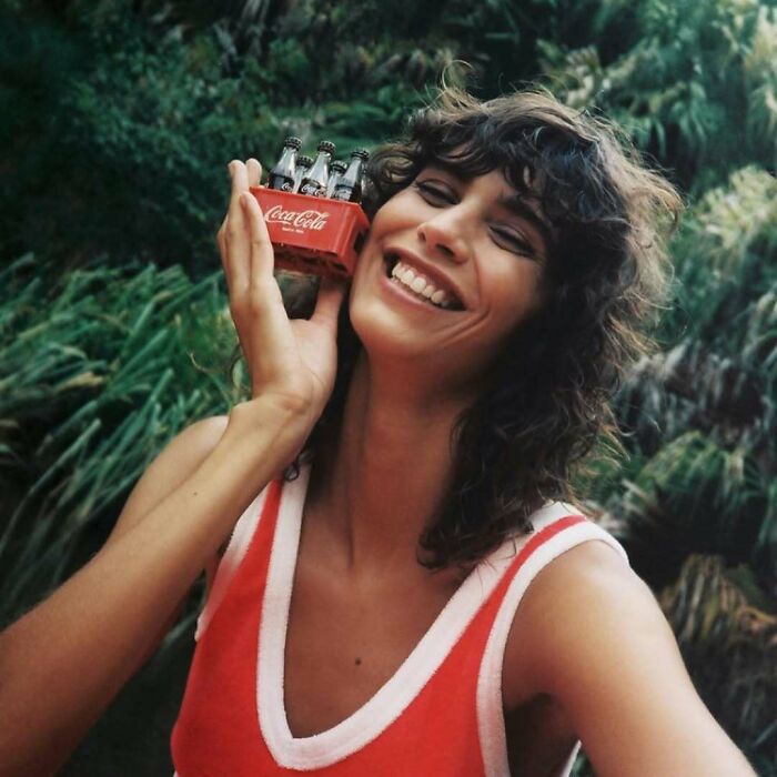 Smiling woman with mini Coca-Cola bottles from Zara website content.