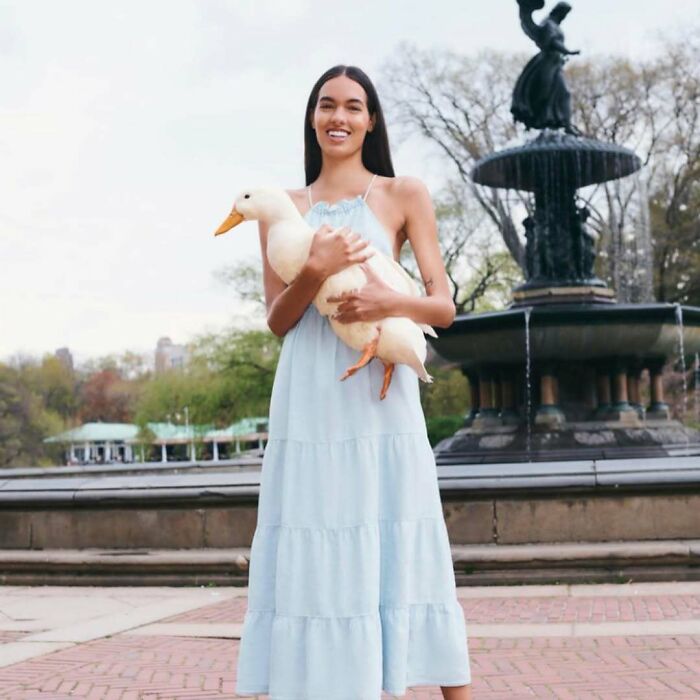 A woman smiling while holding a duck, part of bizarre content on the Zara website.