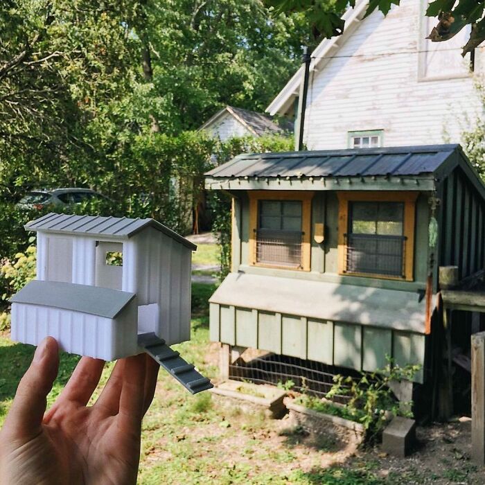 A hand holding a small 3D printing model of a chicken coop next to a real full-sized coop, showcasing amazing creations.