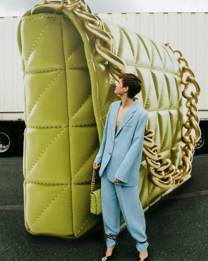 A person in a blue suit stands next to a giant green handbag, representing bizarre content from Zara website.