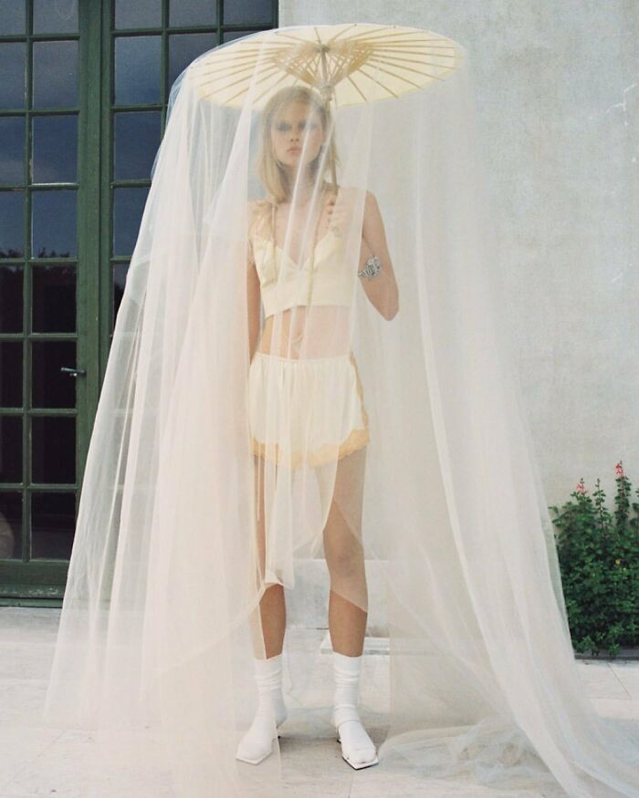 A woman under an umbrella with a long veil, illustrating the bizarre content on Zara website.