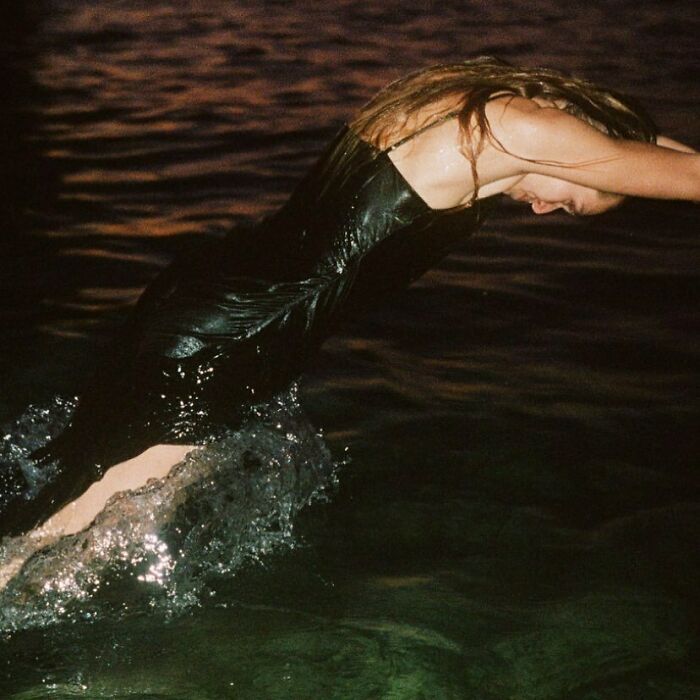 A woman in a black dress falling backwards into dark water, showcasing bizarre content from Zara website.