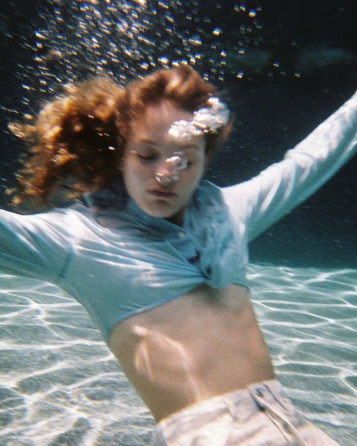 A woman underwater, wearing a light blue top, creating bizarre content for the Zara website.