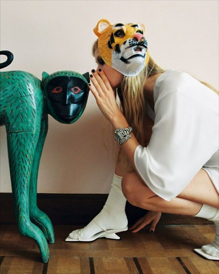 A woman in a tiger mask whispering to a monkey statue, part of the bizarre content on the Zara website.