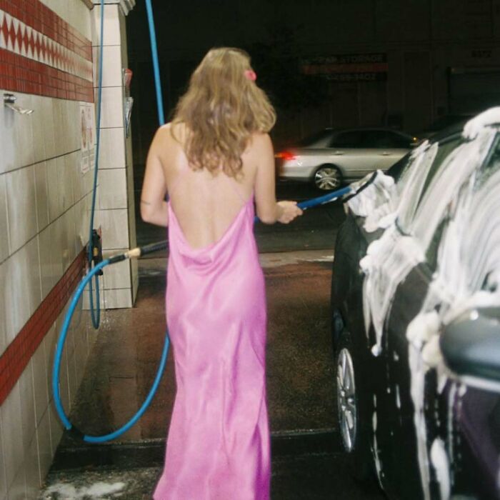 A woman in a pink slip dress washing a car, illustrating bizarre content from the Zara website.