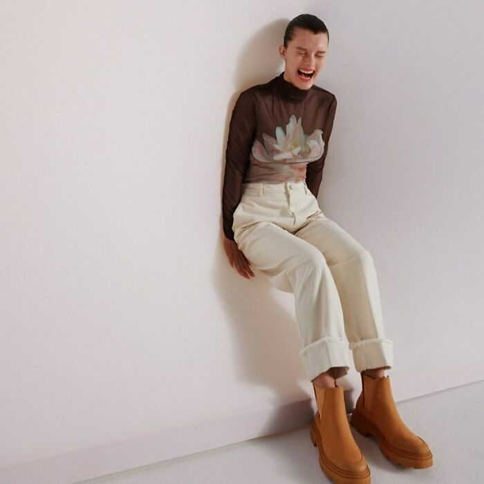 A laughing woman in a sheer top and white pants, highlighting Zara's bizarre content.