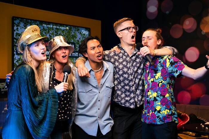 A group of friends enthusiastically singing famous song lyrics together during a karaoke night, capturing the joy of music and shared fun.