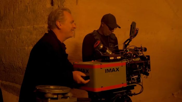 A film director smiling next to an IMAX camera. This image is related to The Odyssey film adaption.
