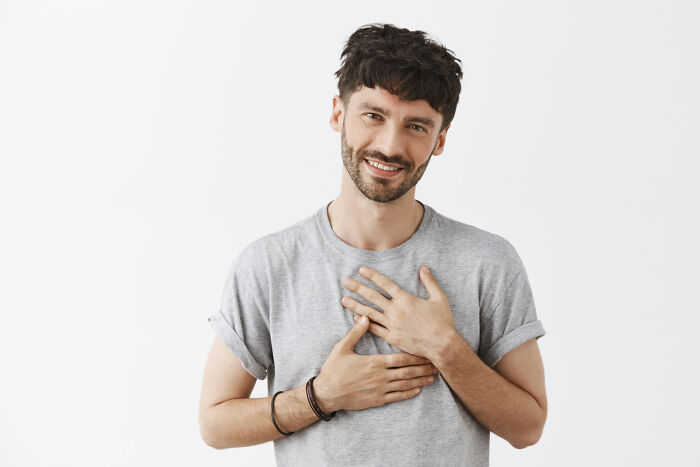 A man with a kind smile, hands on his chest, embodying the feeling of amazing comebacks.