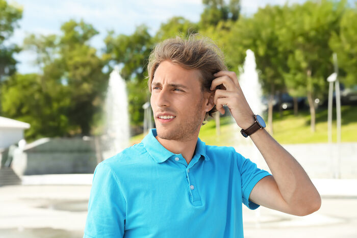 Young man scratching his head, looking thoughtful, representing comebacks and turning insults into art.