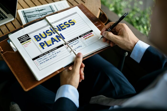 A person writing in a notebook with BUSINESS PLAN visible, highlighting strategic thinking for amazing comebacks.
