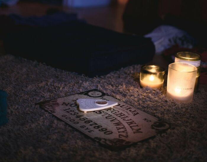 A ouija board on a rug with lit candles, suggesting unsettling childhood memories and spooky experiences.