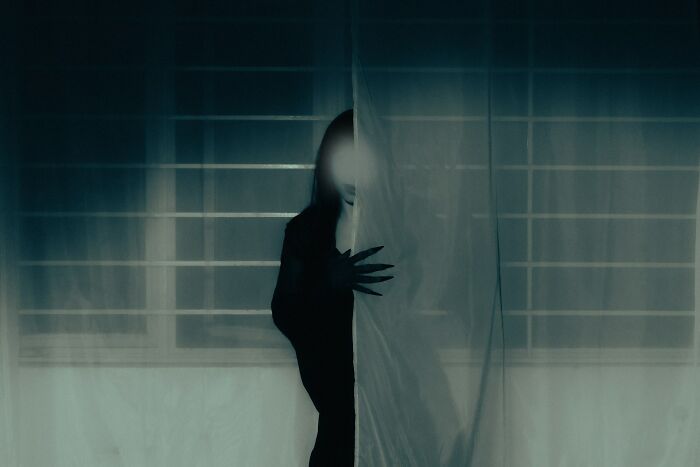 A shadowy figure with long claws behind a curtain, representing unsettling childhood memories that give people chills.