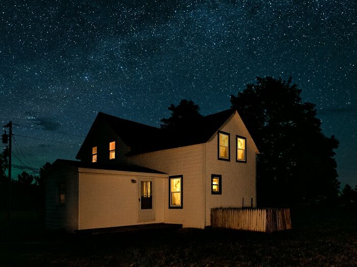 An old house at night with lights on, creating a sense of unsettling childhood memories and chills.