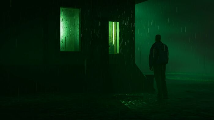 A figure stands in the rain outside a building with glowing green windows, evoking unsettling childhood memories.